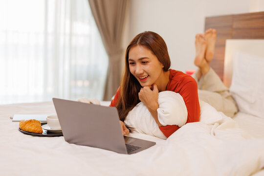 Happy hipster asian gen z teen girl watching tv movie on laptop lying in bed. Smiling teenager make video conference call online, learning online video course, relaxing in bedroom
- Powered by Adobe