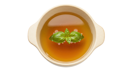 Chicken broth in bowl isolated, clear soup with basil leaf garnish for healthy eating and wellness, on transparent background