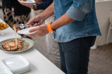 Guests gather around a buffet table at a private event, selecting food from a diverse spread of delicious cuisine served in a catered setting