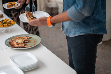 Guests select delicious food from a well-arranged buffet table at a private event party celebrating a special occasion with friends and family enjoying catering services at a gathering