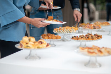 Guests gather around a beautifully arranged buffet table at a private event enjoying a selection of delicious appetizers and finger foods being served by catering staff at a social gathering.
