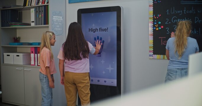 Students Interact With AI Mood Tracker in Modern Class. Girls Use AI Mood Tracker Interactive Digital Screen to Determine Emotional State. Using Technologies in Modern Schools For Emotional Learning.