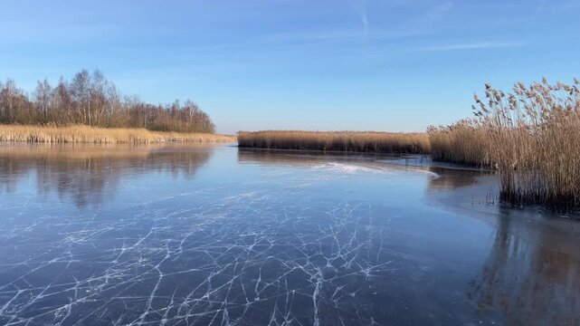 Point Of View ice skating on a frozen lake in nature during a beautiful winter day in Holland.