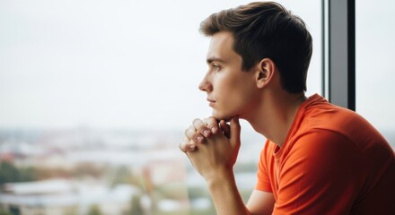 Young man looking out window, deep in thought