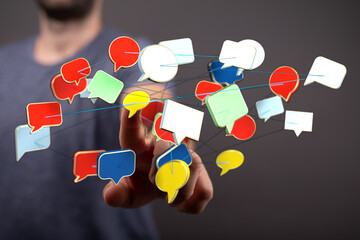 Man's hand interacting with floating speech bubbles, representing communication, social media, and networking.