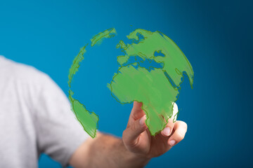 Human hand interacting with a glowing green digital Earth hologram, symbolizing global connection, environmental awareness, and technological so