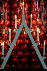 Christmas festive night background with advent candlestick and red Christmas tree balls sparkling in the dark, selective focus
