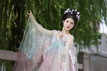 Woman in a flowing pastel hanfu standing gracefully amidst nature.