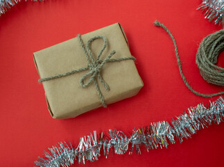 Packing Christmas gifts. Gift, twine and tinsel on a red background.