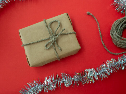 Packing Christmas gifts. Gift, twine and tinsel on a red background.