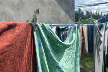washed clothes and linens are drying on a line outside 
closeup