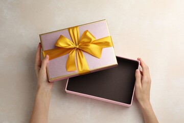 Woman opening gift box on light background, closeup
