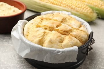 Freshly baked cornbread in cake pan on grey textured table, closeup