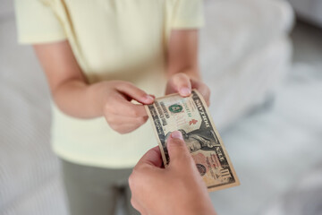 Mother giving pocket money to her daughter at home, closeup