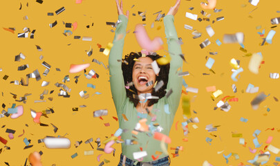 Studio Shot Of Excited Woman Celebrating Big Win Showered In Tinsel Confetti On Yellow Background