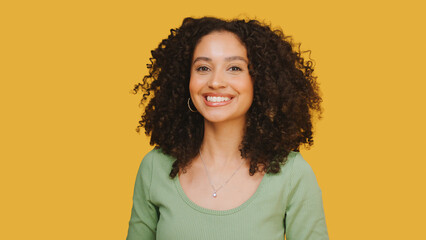 Studio Portrait Of Young Smiling Woman Standing Against Yellow Background