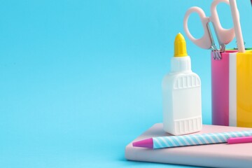 Glue and other stationery on light blue background. Space for text