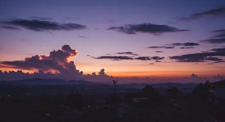 Fototapeta premium Vibrant sunset sky with clouds silhouetted over rolling hills