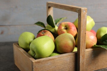 Fresh ripe apples in crate on grey table, closeup