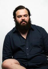 Overweight man with beard and acne scars, sitting pose, white background