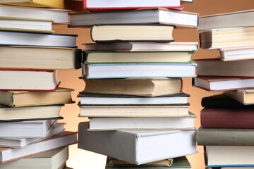 Many stacked books against brown background, closeup