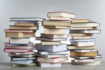 Many stacked books on table against light grey background