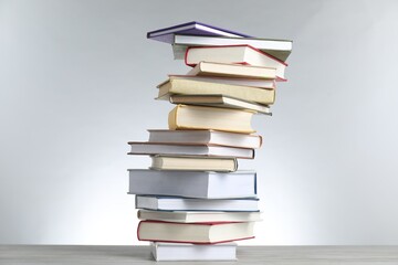 Many stacked books on table against light grey background
