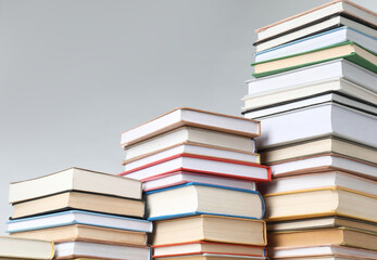 Many stacked books against light grey background, closeup. Space for text