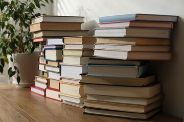 Many stacked books on wooden table, closeup