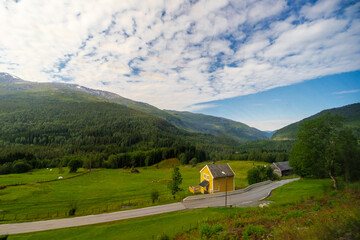 Amazing landscape of the Norwegian country during a perfect summer holiday with wonderful green fields, perfect cloudscape and breath-taking panoramic view as far as you can see with mountains and fjo