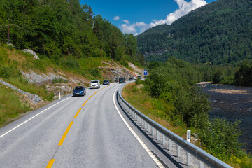 Naklejka premium Amazing landscape of the Norwegian country during a perfect summer holiday with wonderful green fields, perfect cloudscape and breath-taking panoramic view as far as you can see with mountains and fjo