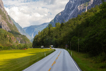 Amazing landscape of the Norwegian country during a perfect summer holiday with wonderful green fields, perfect cloudscape and breath-taking panoramic view as far as you can see with mountains and fjo