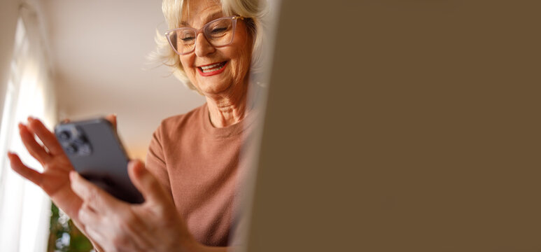 Low angle view of happy elderly woman attending online therapy for emotional support on smart phone at home - Powered by Adobe