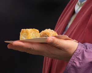 Close-up of a visitors hand holding a paper tray with pieces of traditional Mediterranean baklava at farmers market Naplavka in the center of Prague, lifestyle and authentic street food experience.