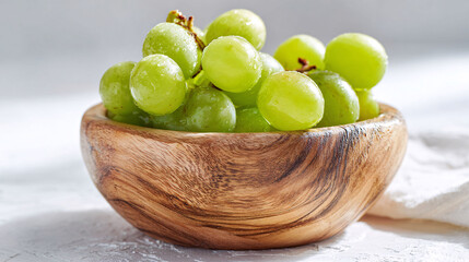 Fresh green grapes in a rustic wooden bowl, healthy snack, bright light, still life.