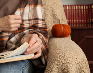 A decorative pumpkin next to a woman reading.