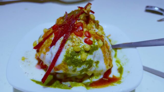 The plate of raj kachori chaat with curd and toppings is shown with a moving around view, emphasizing details.