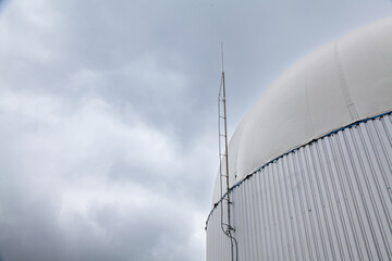 Dunkle Wolken über einem Biogas Fermenter mit Blitzableiter