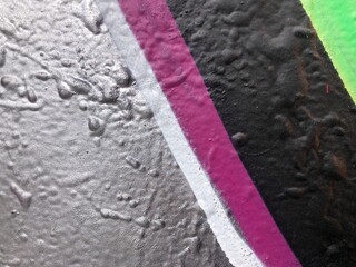 Macro close-up of a graffiti wall texture featuring splattered gray, black, magenta, and green spray paint wallpaper background