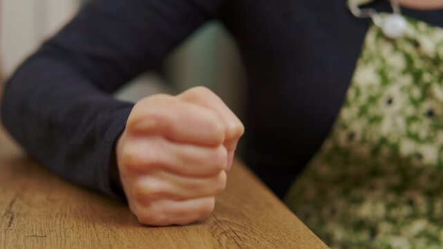 close up view of woman fist pounding on table.