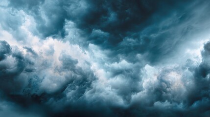 Obraz premium A dramatic sky filled with dark, churning storm clouds in shades of deep blue, grey, and white, suggesting powerful, impending weather, blurred blue background