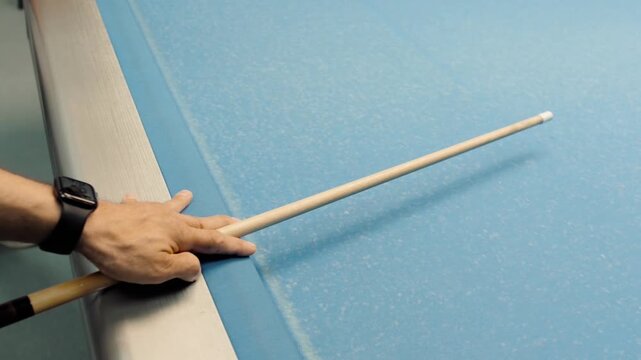 Man playing billiards aiming with cue stick on blue pool table