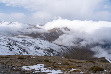 Dramatic high mountain landscape with snow, rocks and low clouds