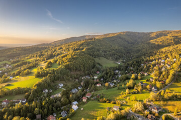 Aerial panoramic view of a mountain village in Beskid Mountains, Poland at golden hour