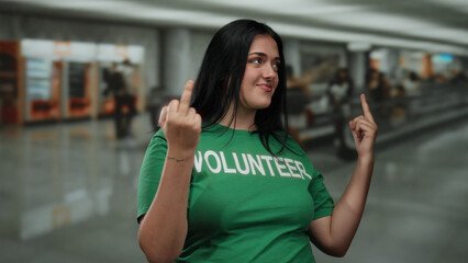 Woman in green volunteer shirt making rude gesture at airport terminal reflecting urban attitude...