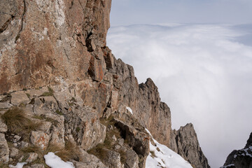 Dramatic high mountain landscape with snow, rocks and low clouds