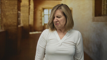 Woman caucasian middle aged scrunches nose and wrinkles forehead on old town cobblestone street;...
