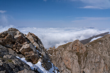 Dramatic high mountain landscape with snow, rocks and low clouds