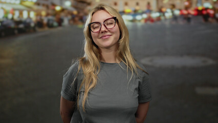 Fototapeta premium Young woman smiling with closed eyes and hands on chest, standing on a lively city street outdoor in a casual setting, exuding happiness and confidence.