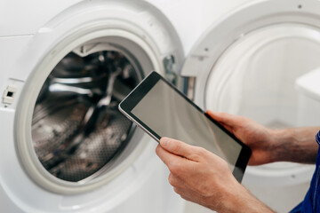 Repairing a washing machine with a tablet in a modern laundry room